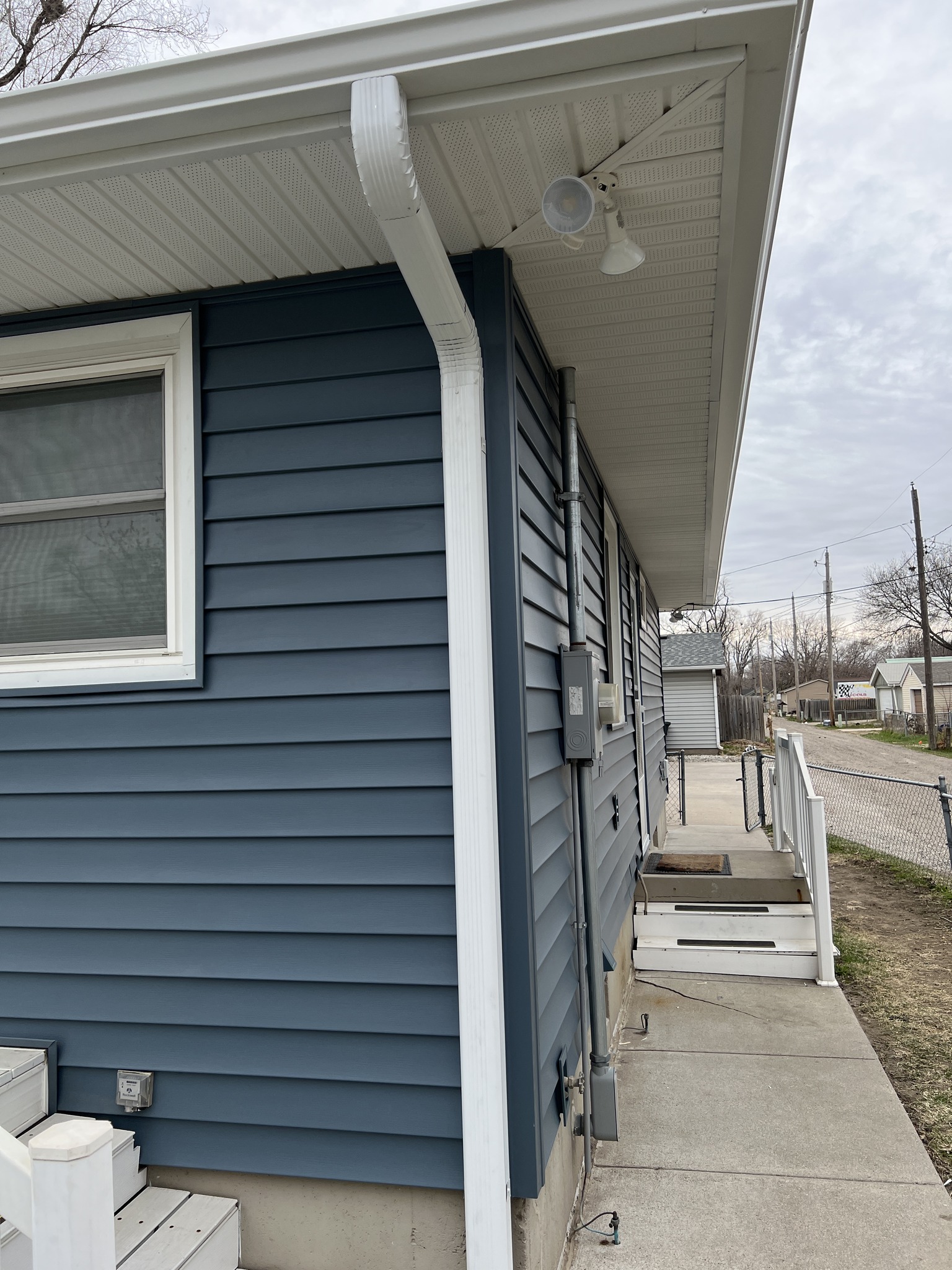 Finished blue siding with white soffit, fascia, and gutter detail.