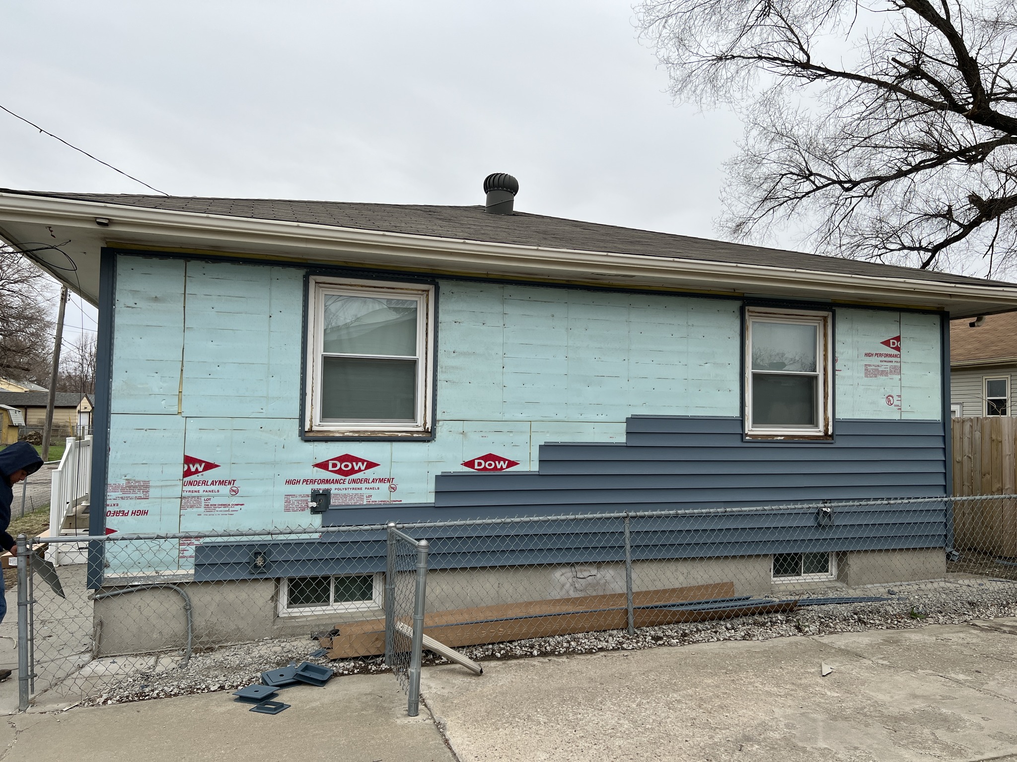 Blue siding panels being installed on a residential exterior wall.