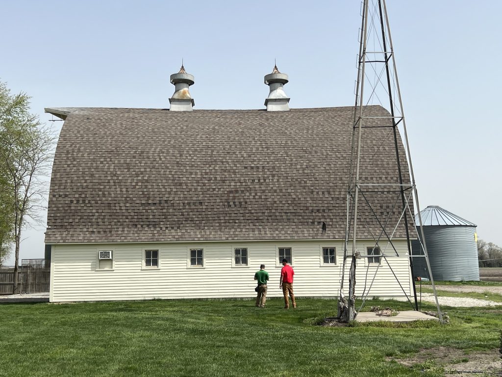 Large barn roof before replacement work with crew reviewing the exterior.