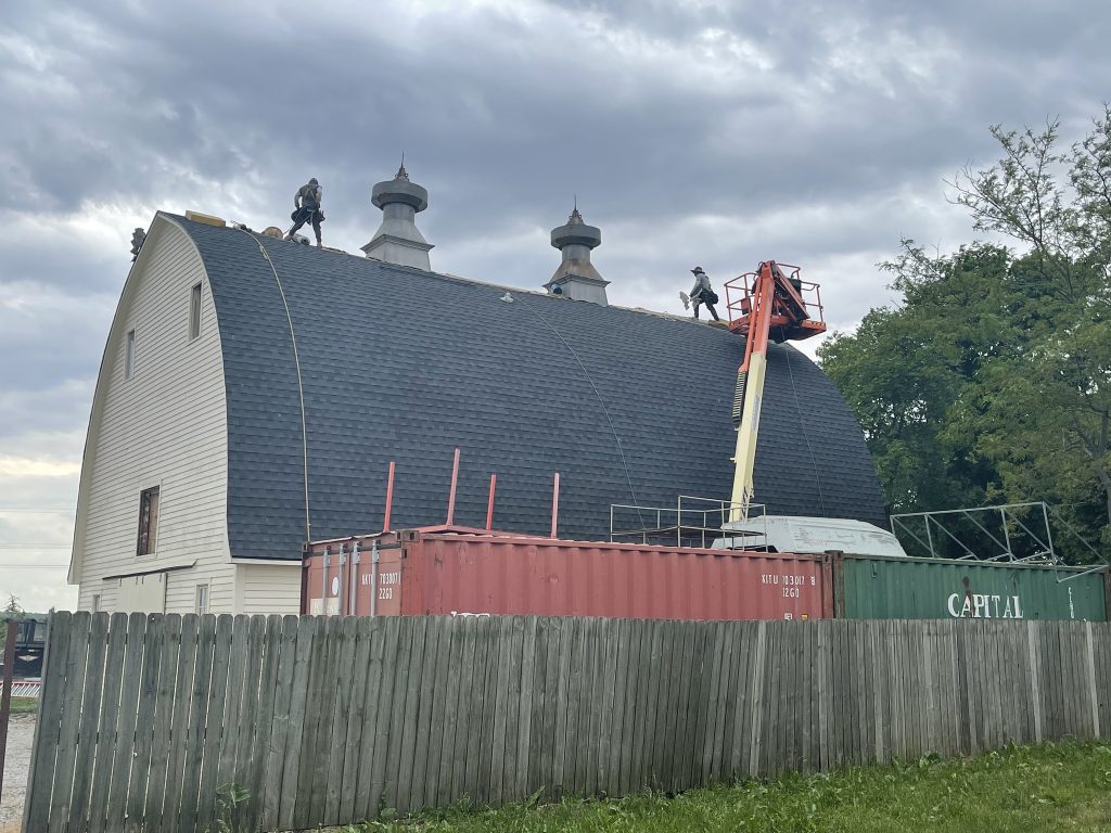 Roofing crew working from a lift on a steep barn roof project.