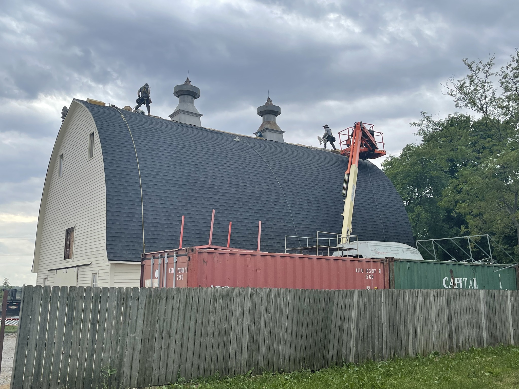 Roofing crew working from a lift on a steep barn roof project.