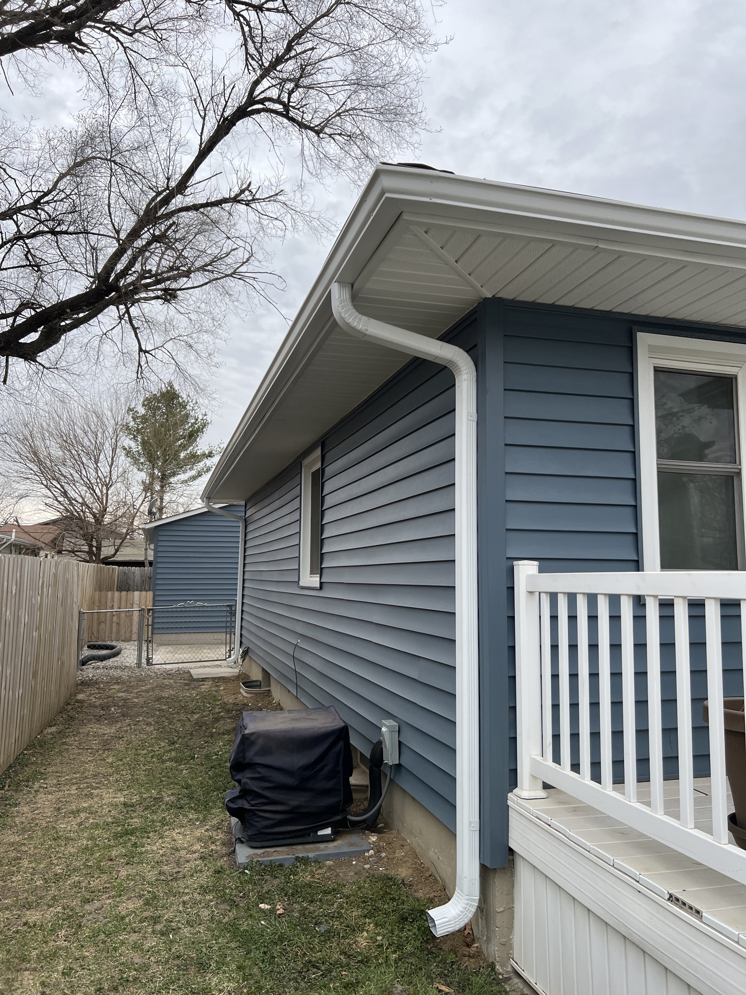 Finished blue siding with white gutter downspout on a residential home.