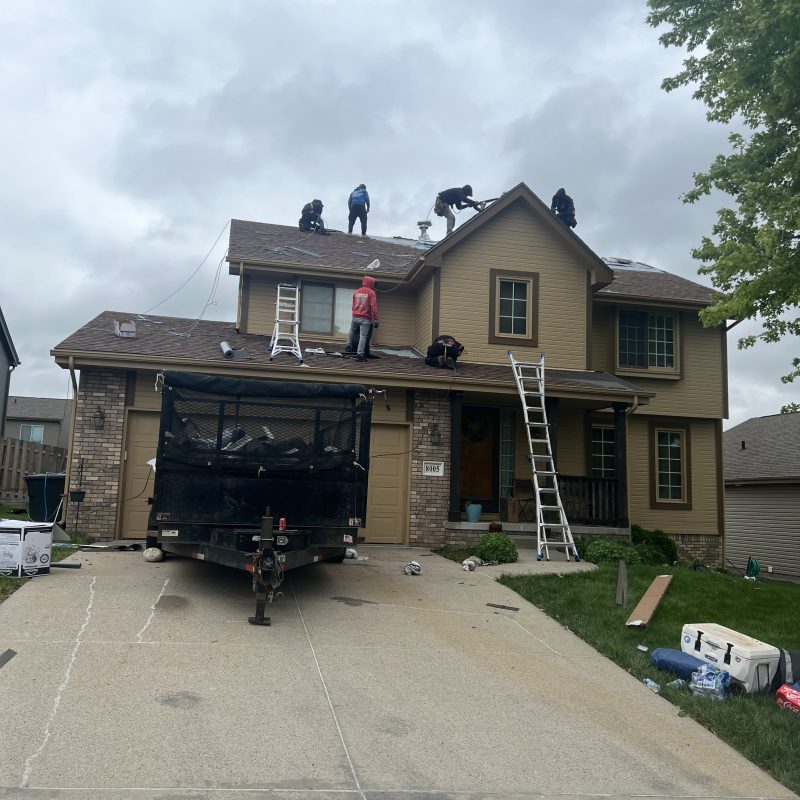 Residential roof replacement project with ladders and crew on the roof.