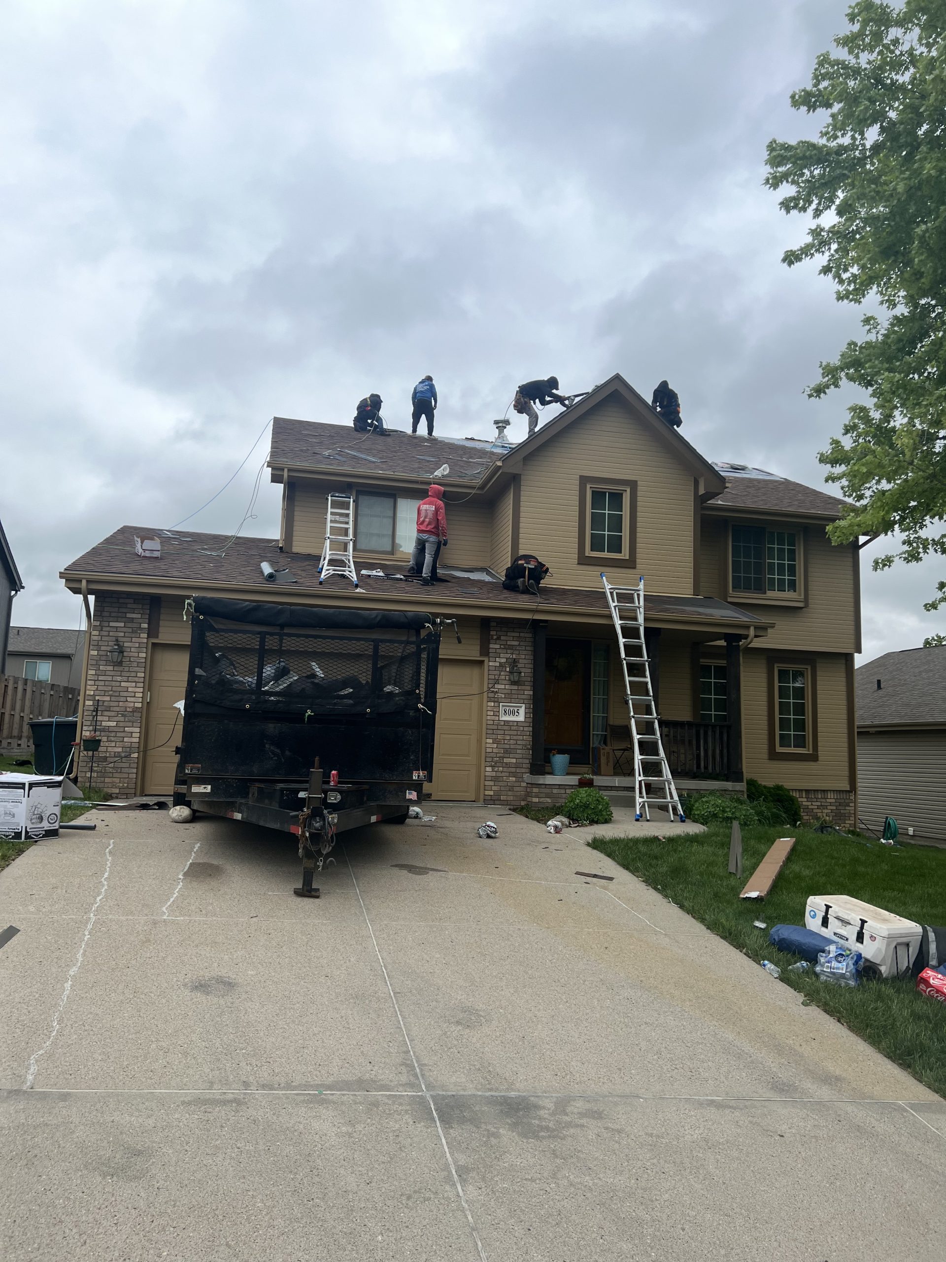 Residential roof replacement project with ladders and crew on the roof.