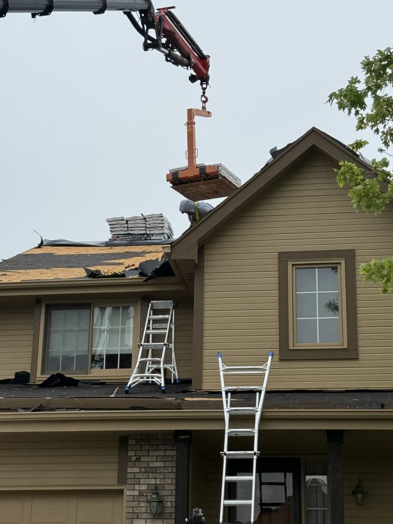 Roofing materials being lifted onto a residential roof during replacement.