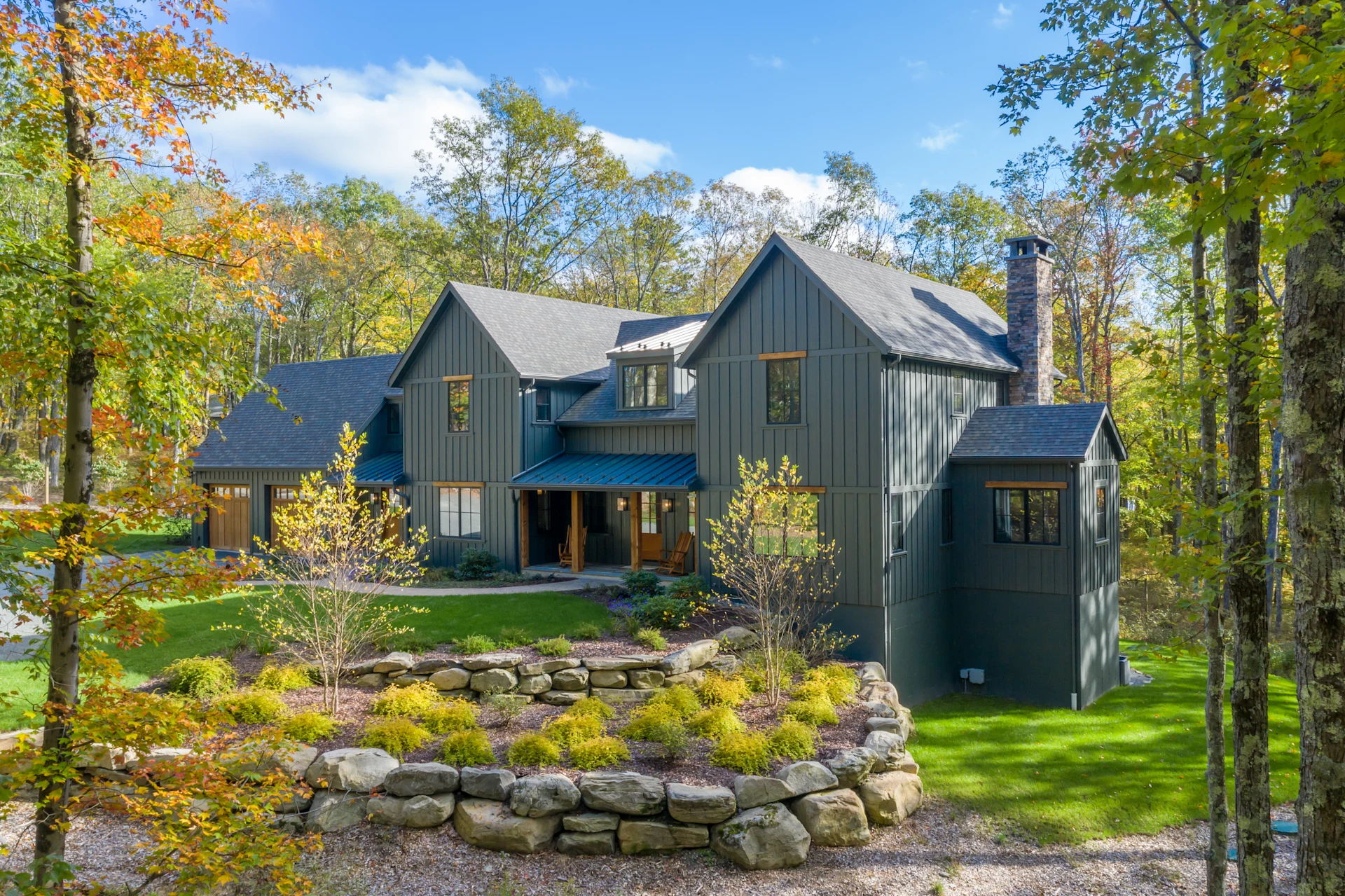 Finished home with dark James Hardie siding and board-and-batten styling, surrounded by trees and stone landscaping.